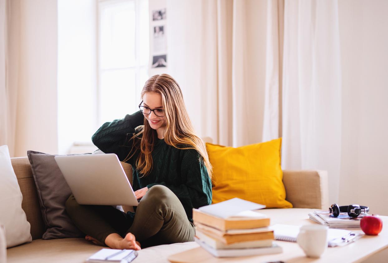 girl sitting cross legged on a coach at laptop