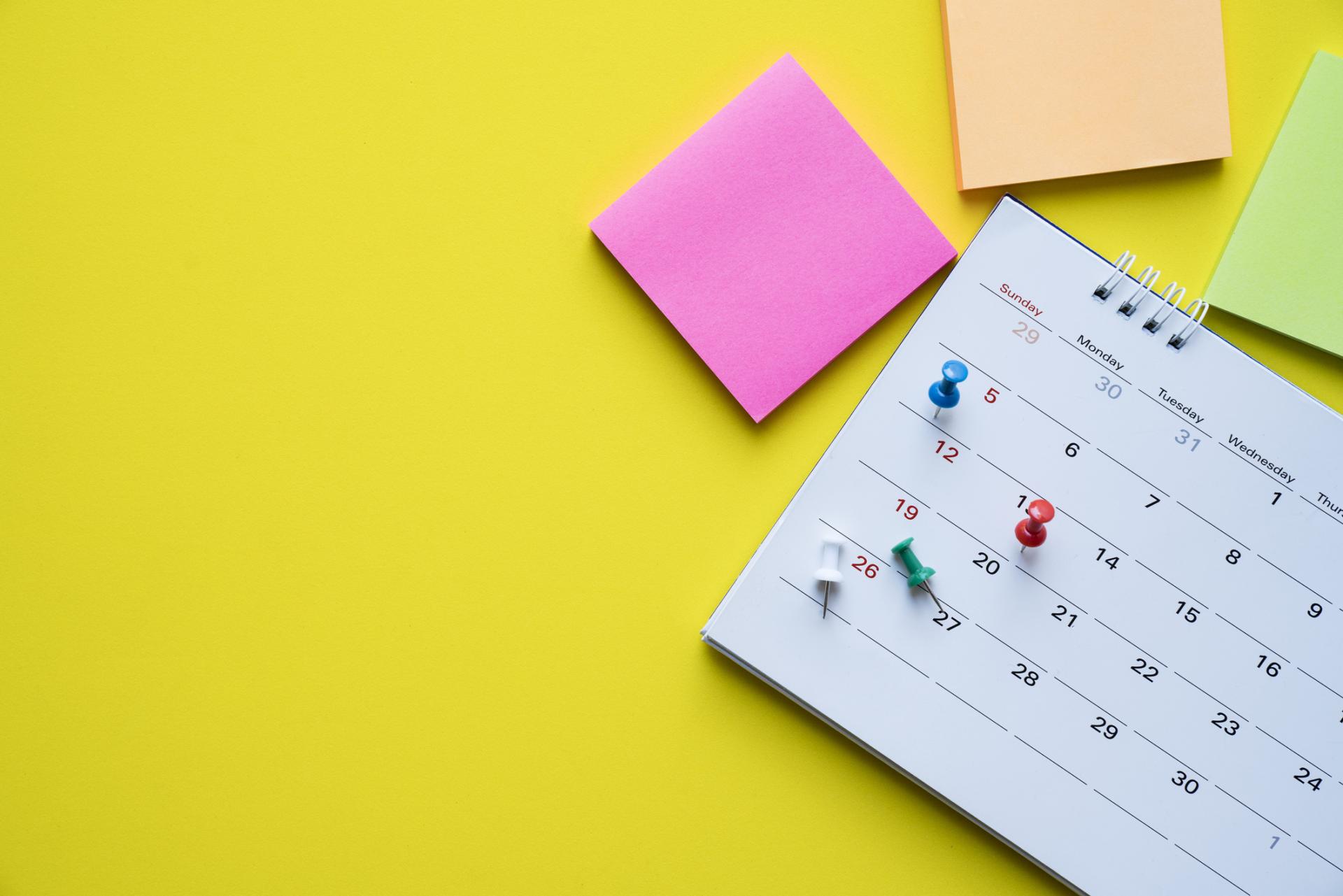 notes and a calendar on a yellow desk