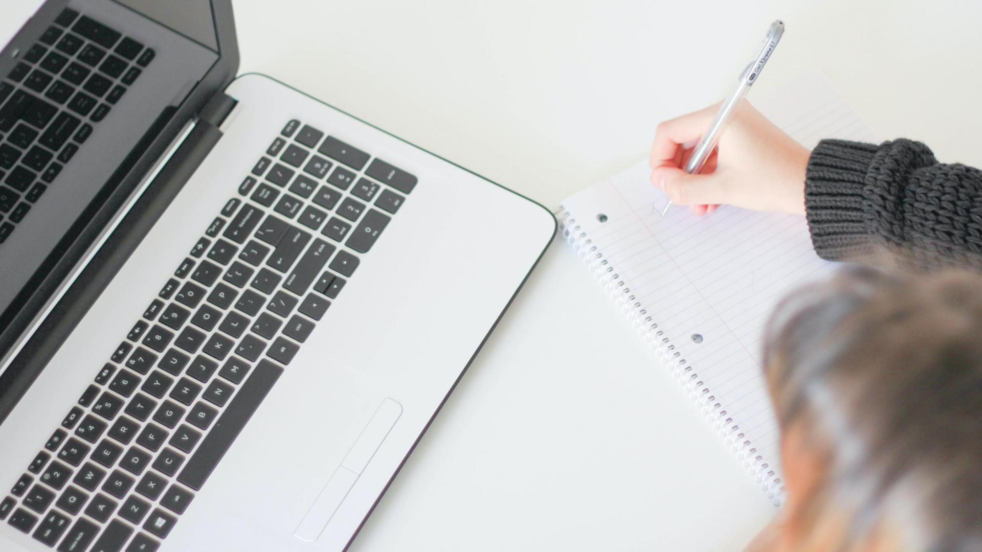 Woman looking at laptop taking notes