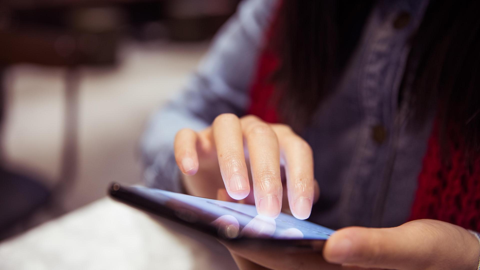 A female interacting with a phone. 