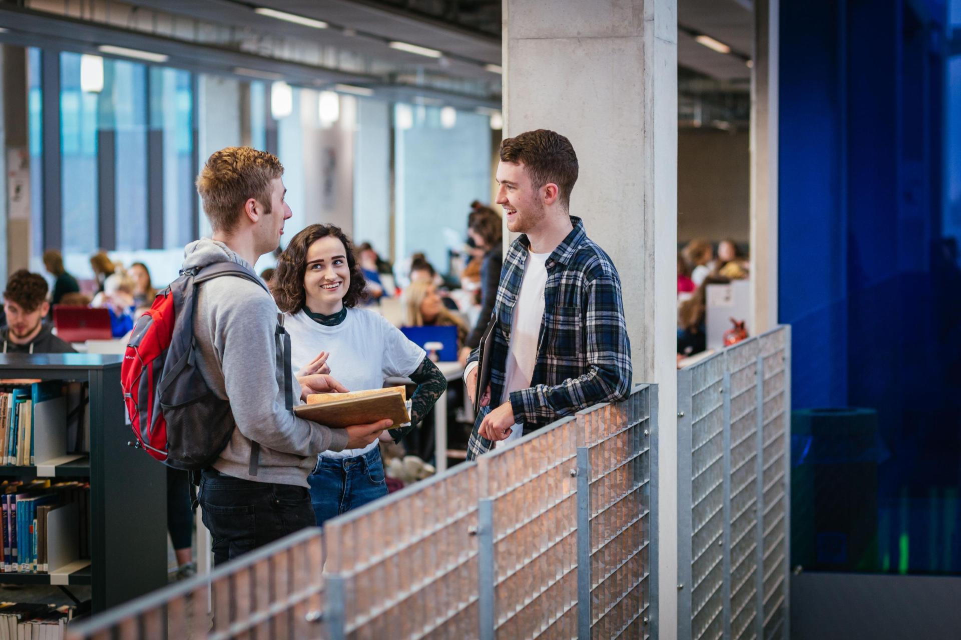 A photo of students chatting in a library.