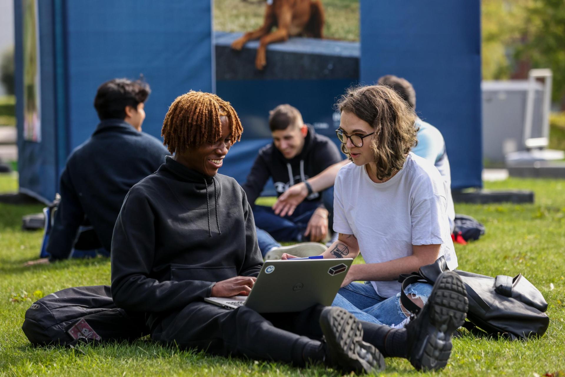 Students sitting on a lawn chatting.