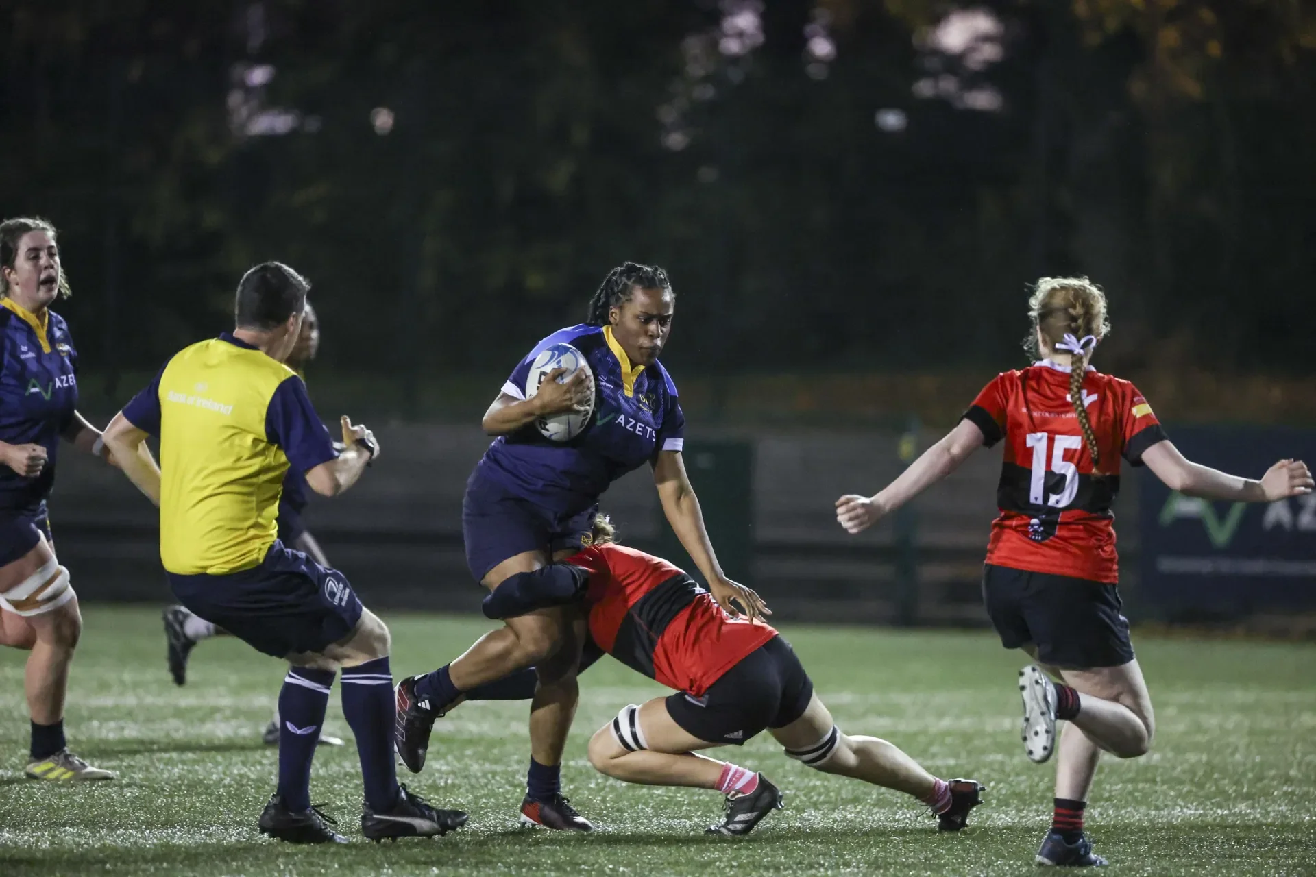 Female rugby player breaking through a tackle