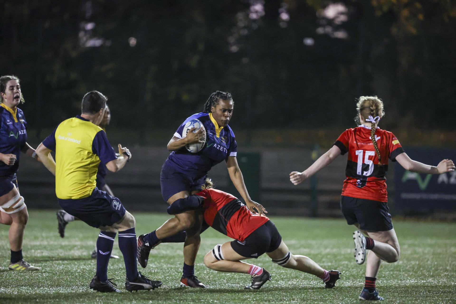 Female rugby player breaking through a tackle