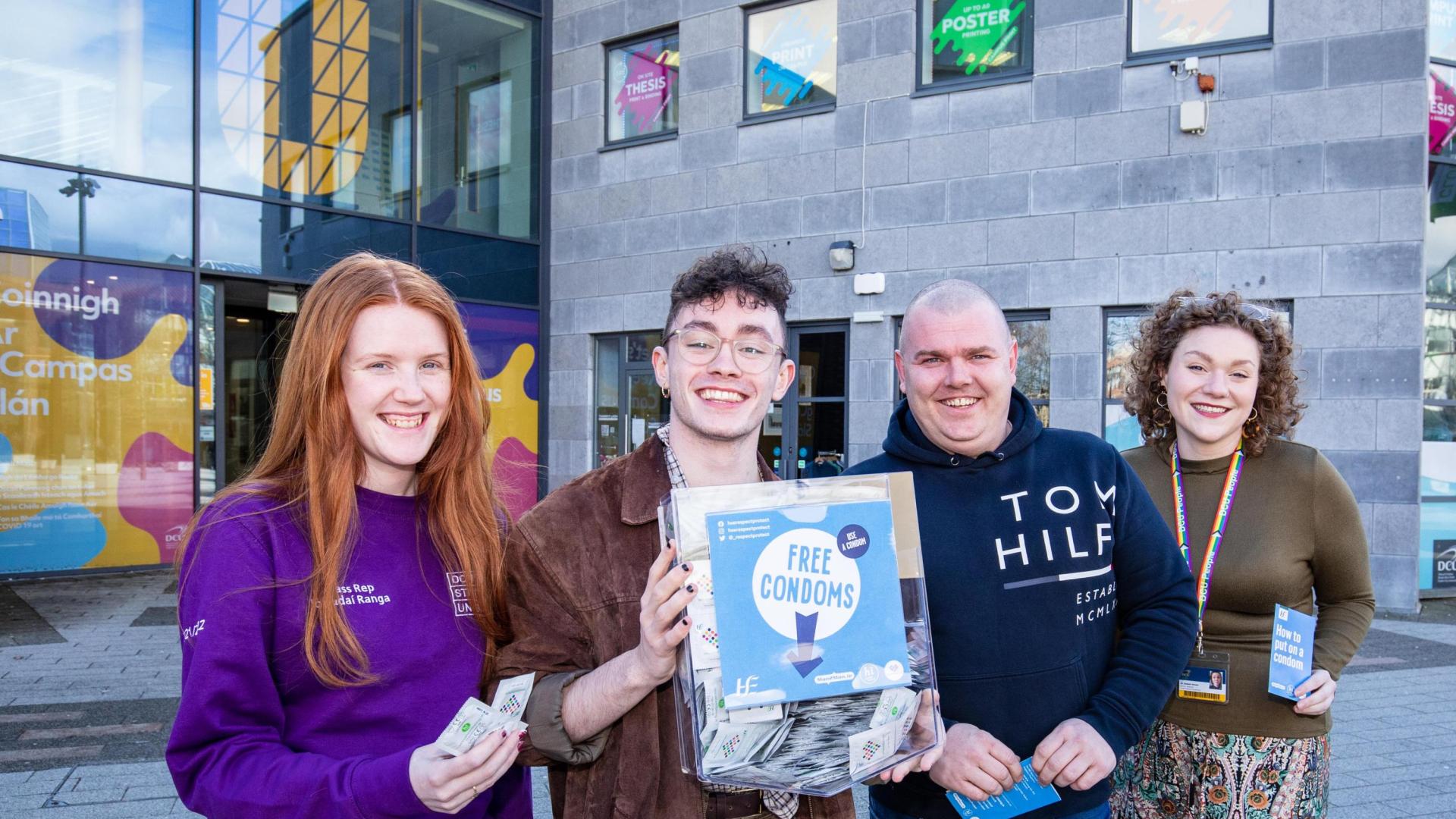 image of 4 people holding a condom dispenser