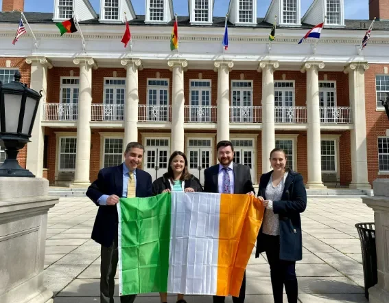 two men and two women in front of a building holding an Irish flag
