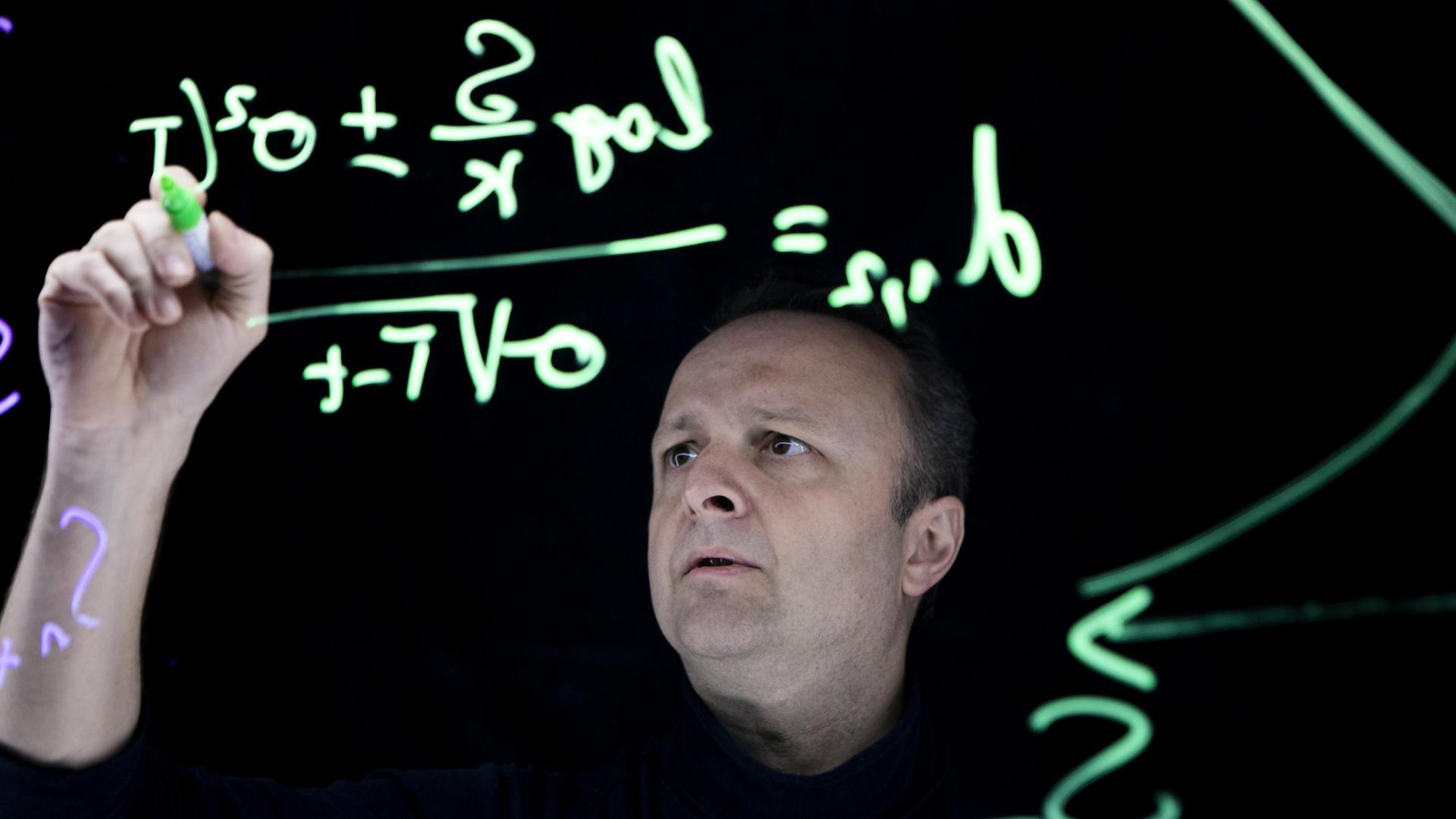 Researcher writing maths on blackboard