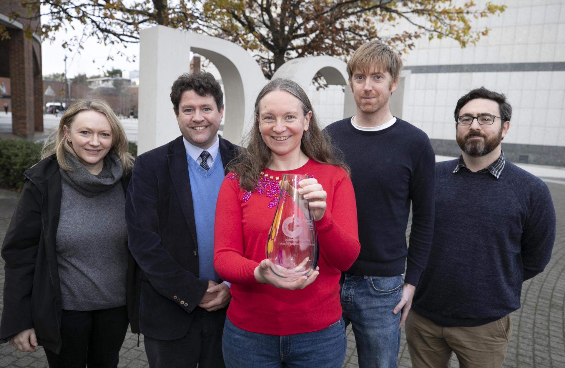 A group of five staff members from DCU School of Maths with their Athena Swan award