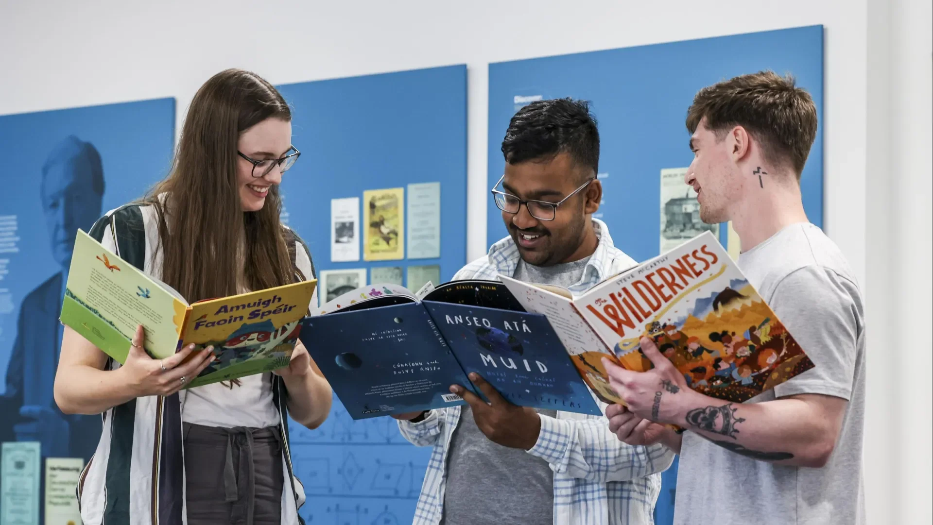 Image of three people reading books from the Children's Books Ireland Collection at DCU Special Collections & Archives