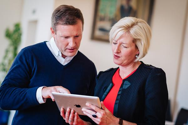 2 people chatting while looking at a tablet