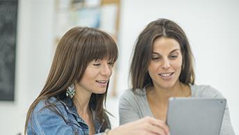 2 people talking while looking at tablet