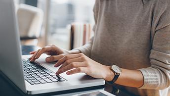 A student typing on a laptop. 