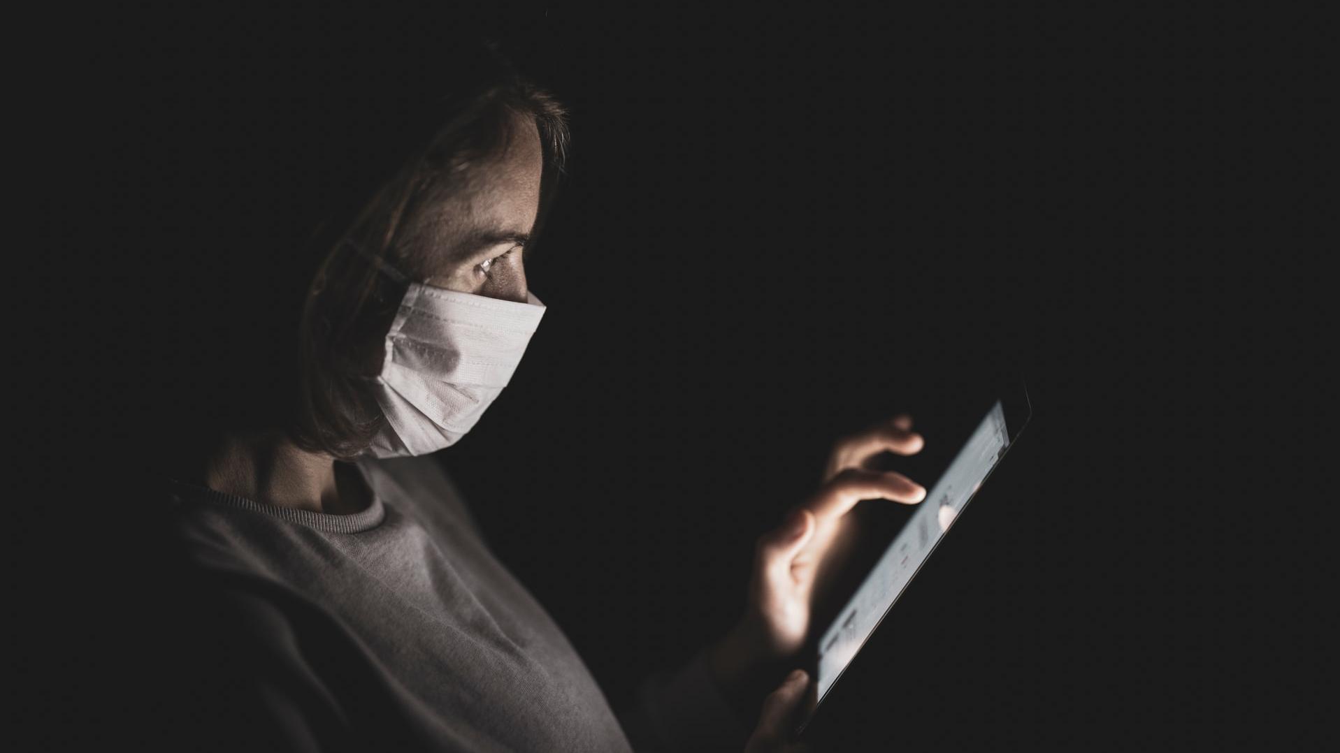 Image showing person wearing mask while using tablet