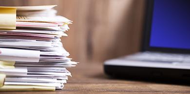 files stacked in front of a laptop computer