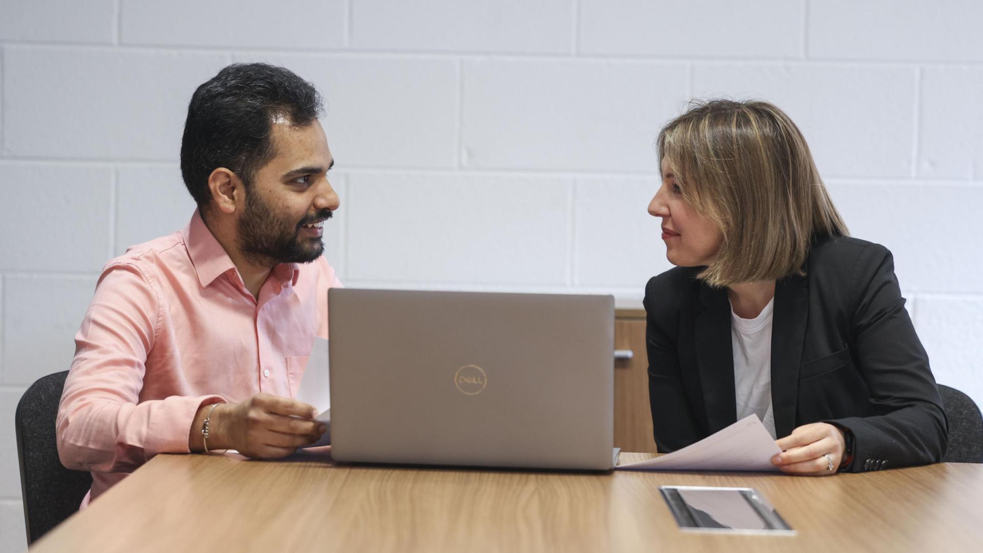 Man and woman talking with laptop open