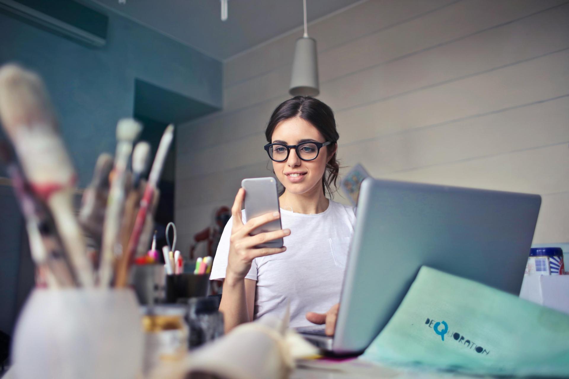 Woman working on laptop and checking phone
