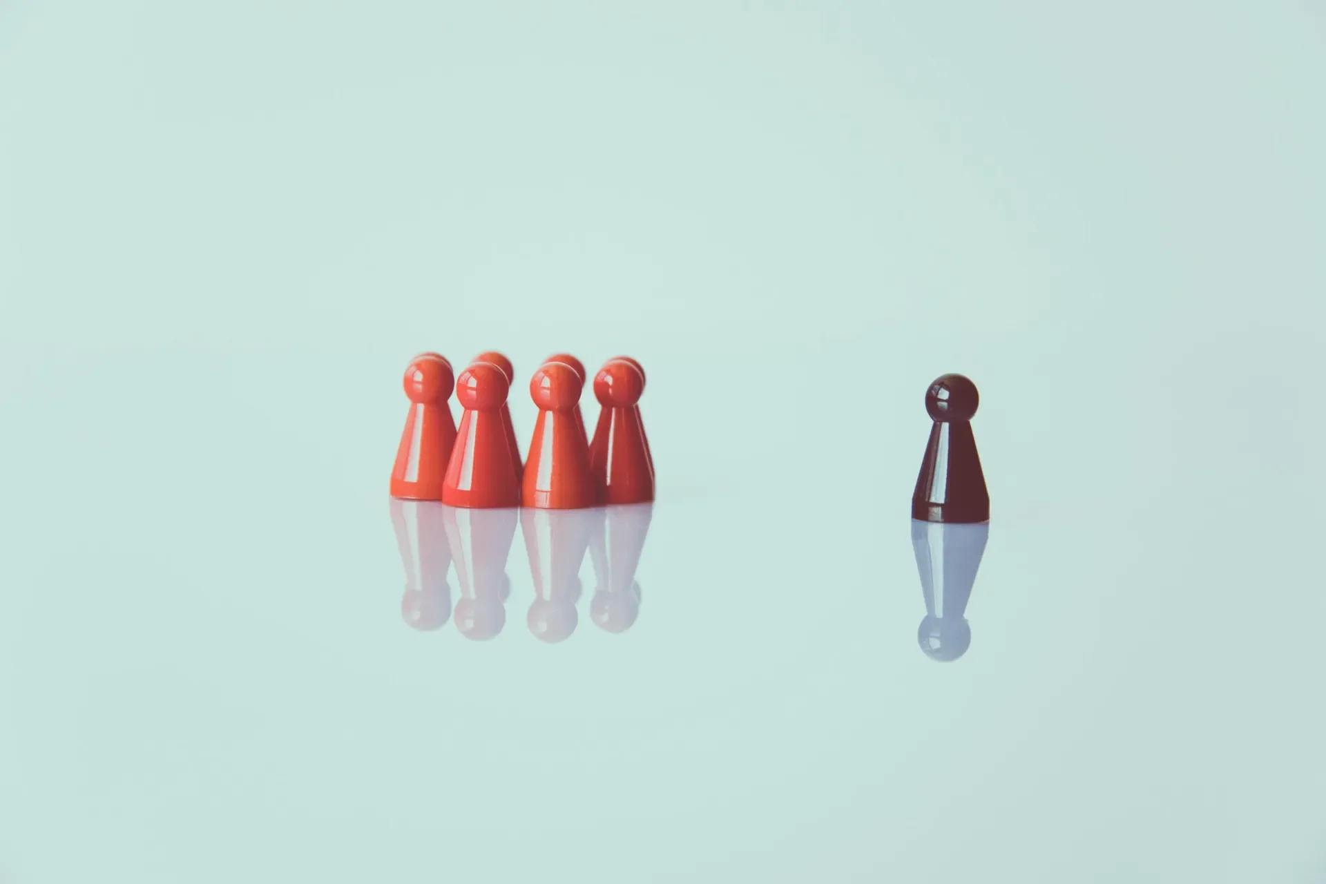 four red figures placed together facing one black figure in the distance