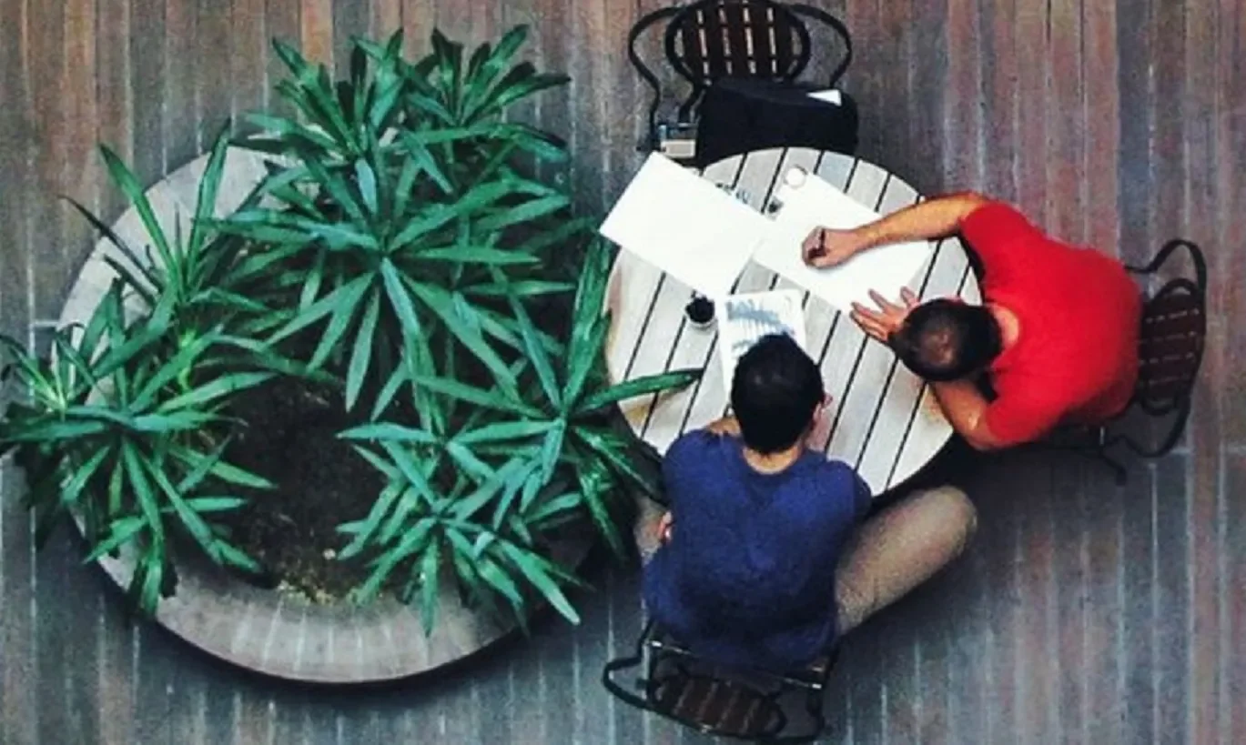 Two people chatting at table, view from above