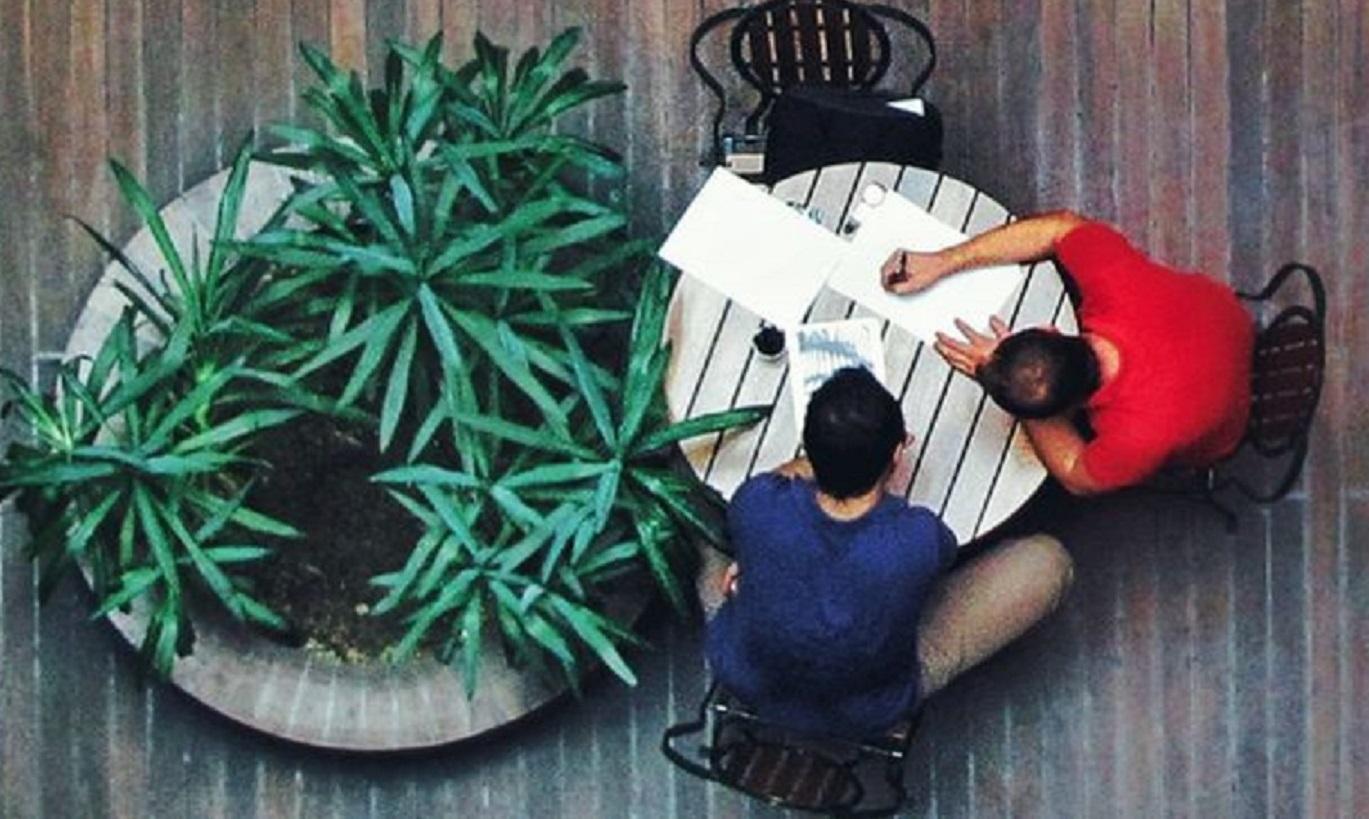 Two people chatting at table, view from above