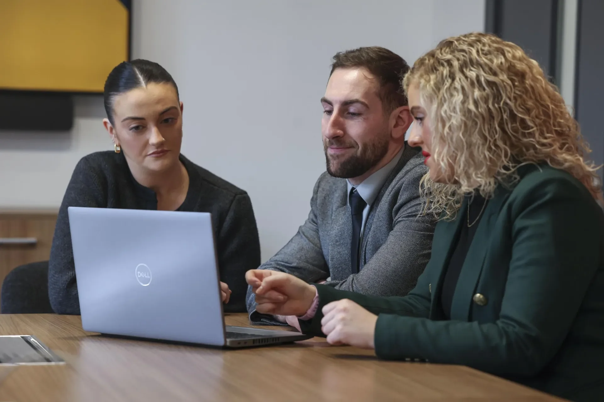 three colleagues in boardroom looking at laptop 
