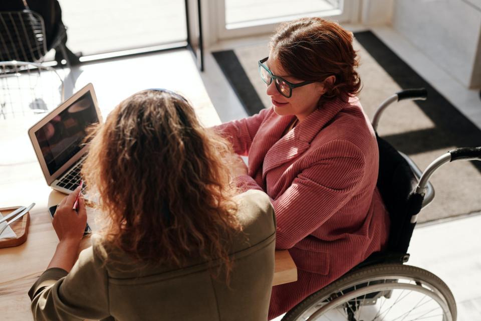 Two people sitting at desk viewing a tablet