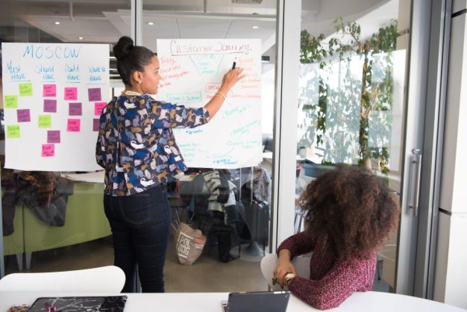 Person showing details on a flipchart paper taped to glass window