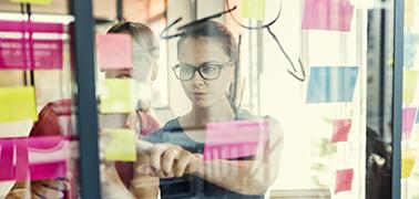 Colleague arranging post its on glass pane