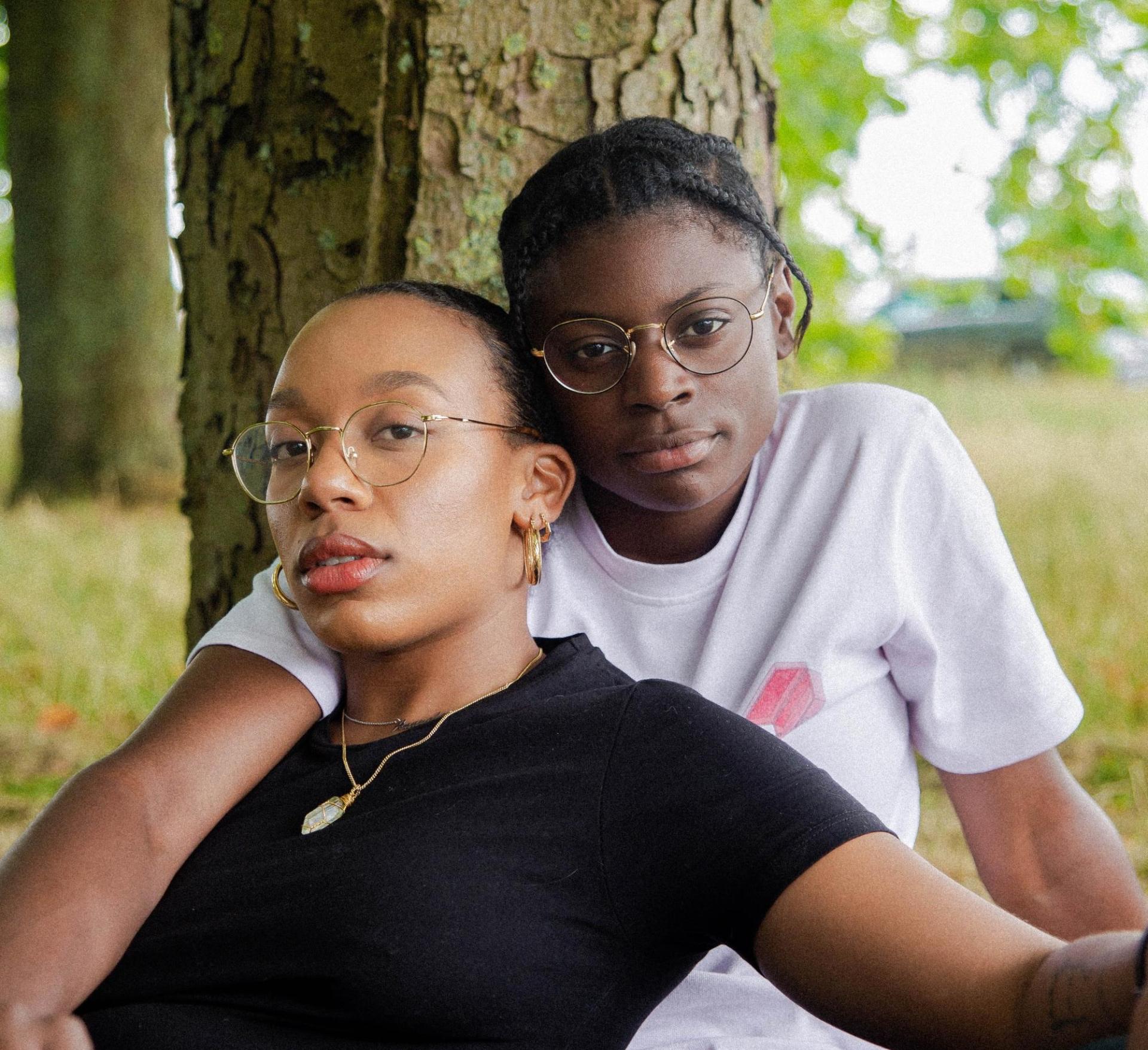 2 People holding each other sitting at a tree