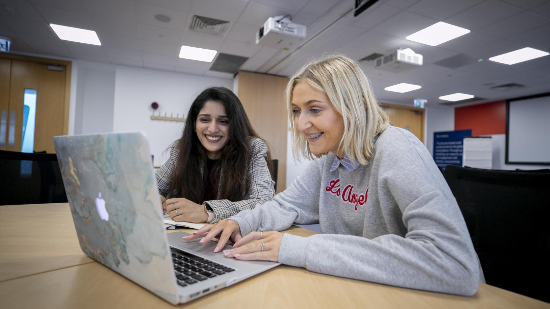 Shows two female students with laptop
