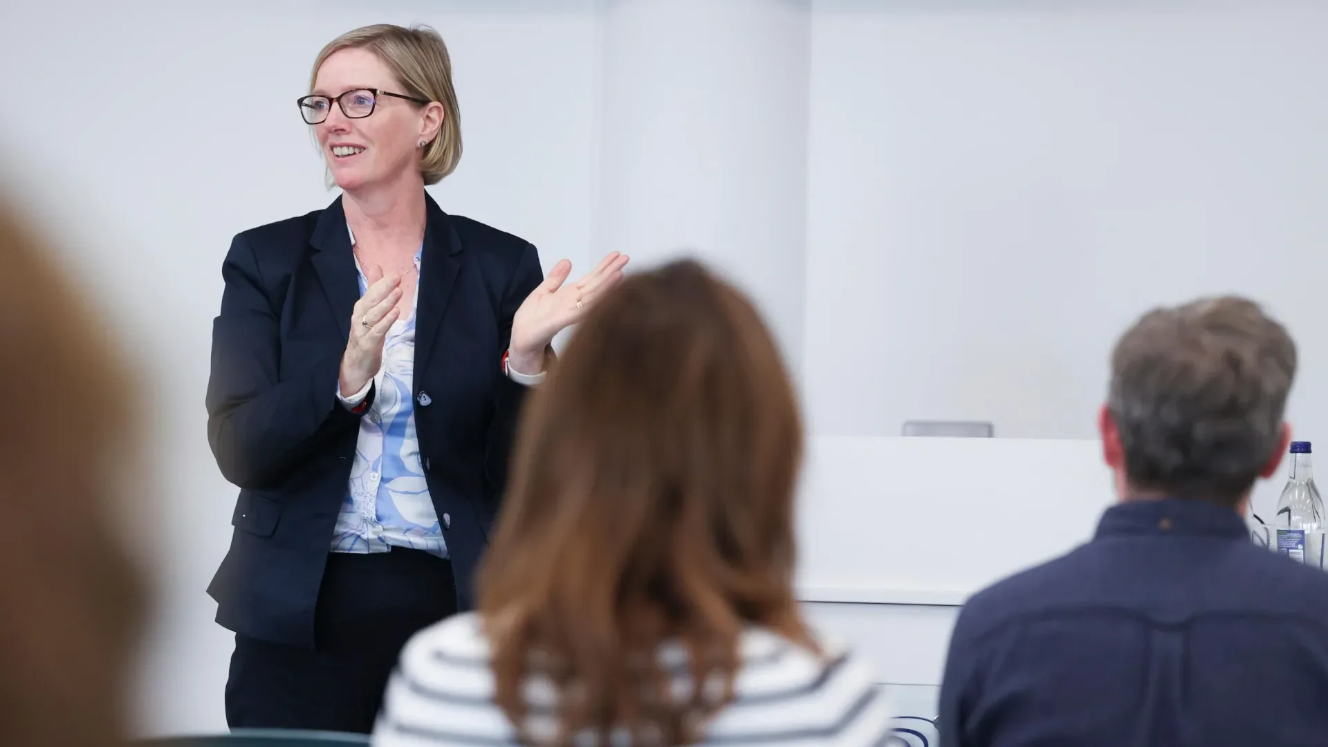 Shows woman speaking to crowd at conference style academic event