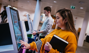 Two students borrow books using the library's self-issue machines