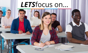 Students sit at tables facing forwards as if attending a training session