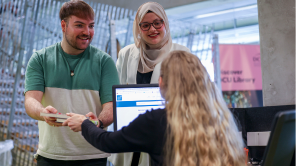 students returning books to library staff at issuedesk in Cregan Library