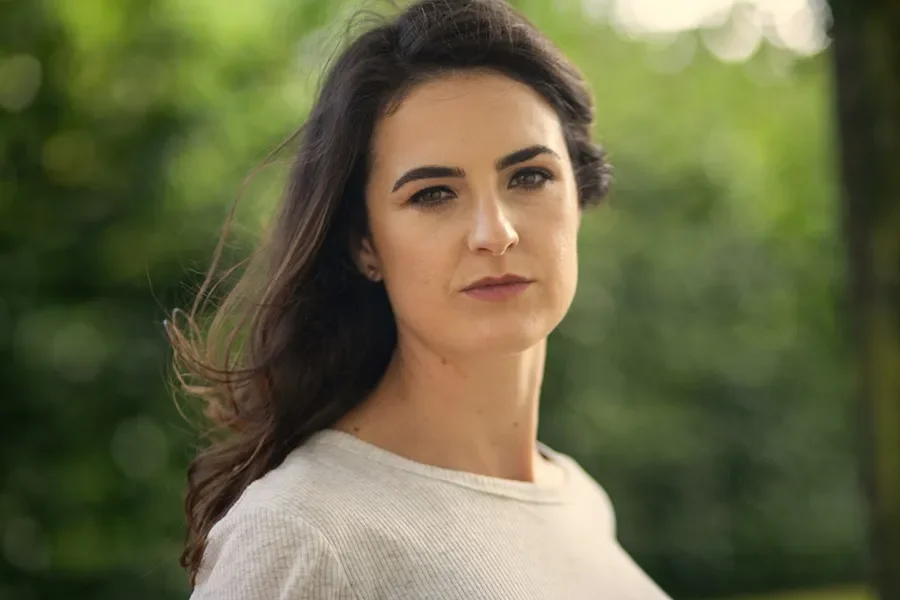 Ciara Ní É - Irish Language Writer in Residence. Woman with long brown hair wearing a cream top stares into the camera lens