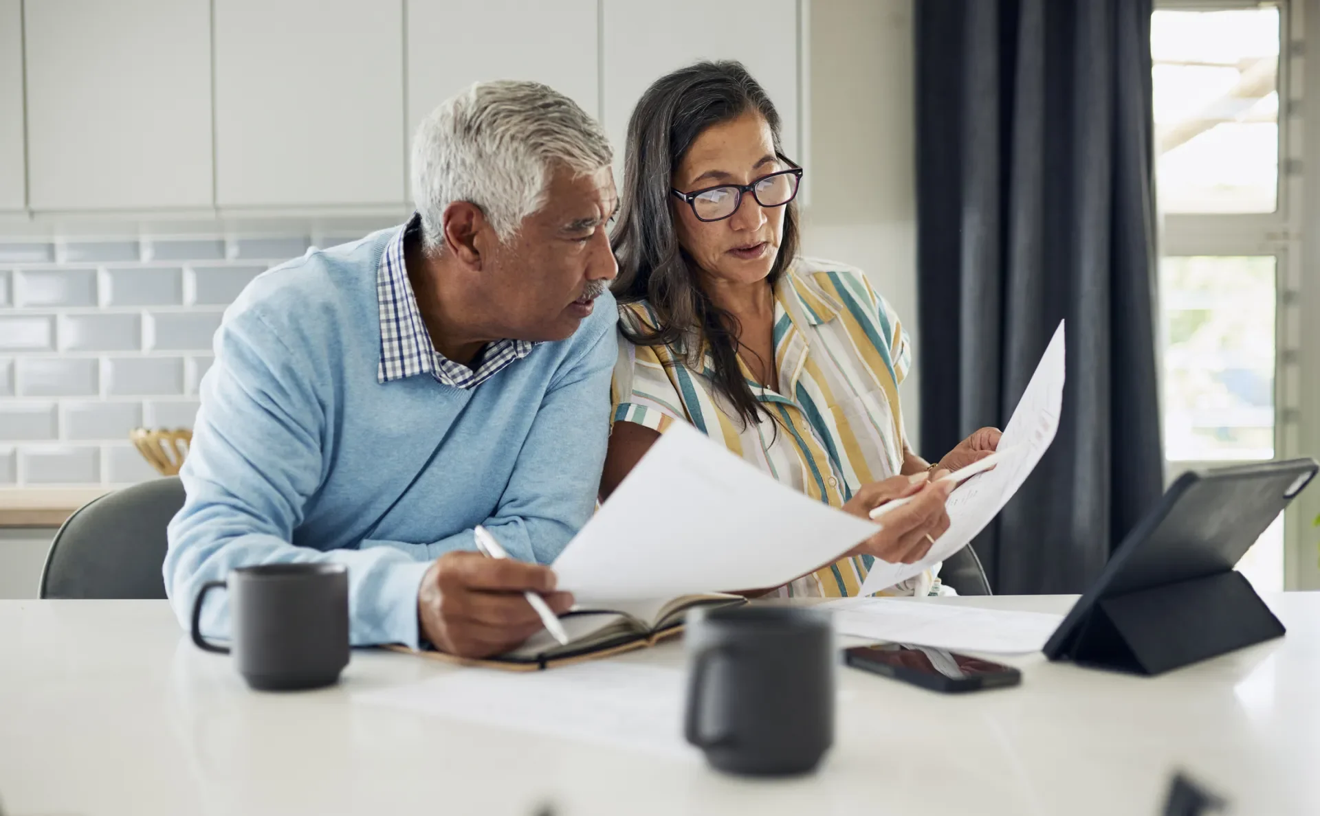An older couple review pension details in their kitchen
