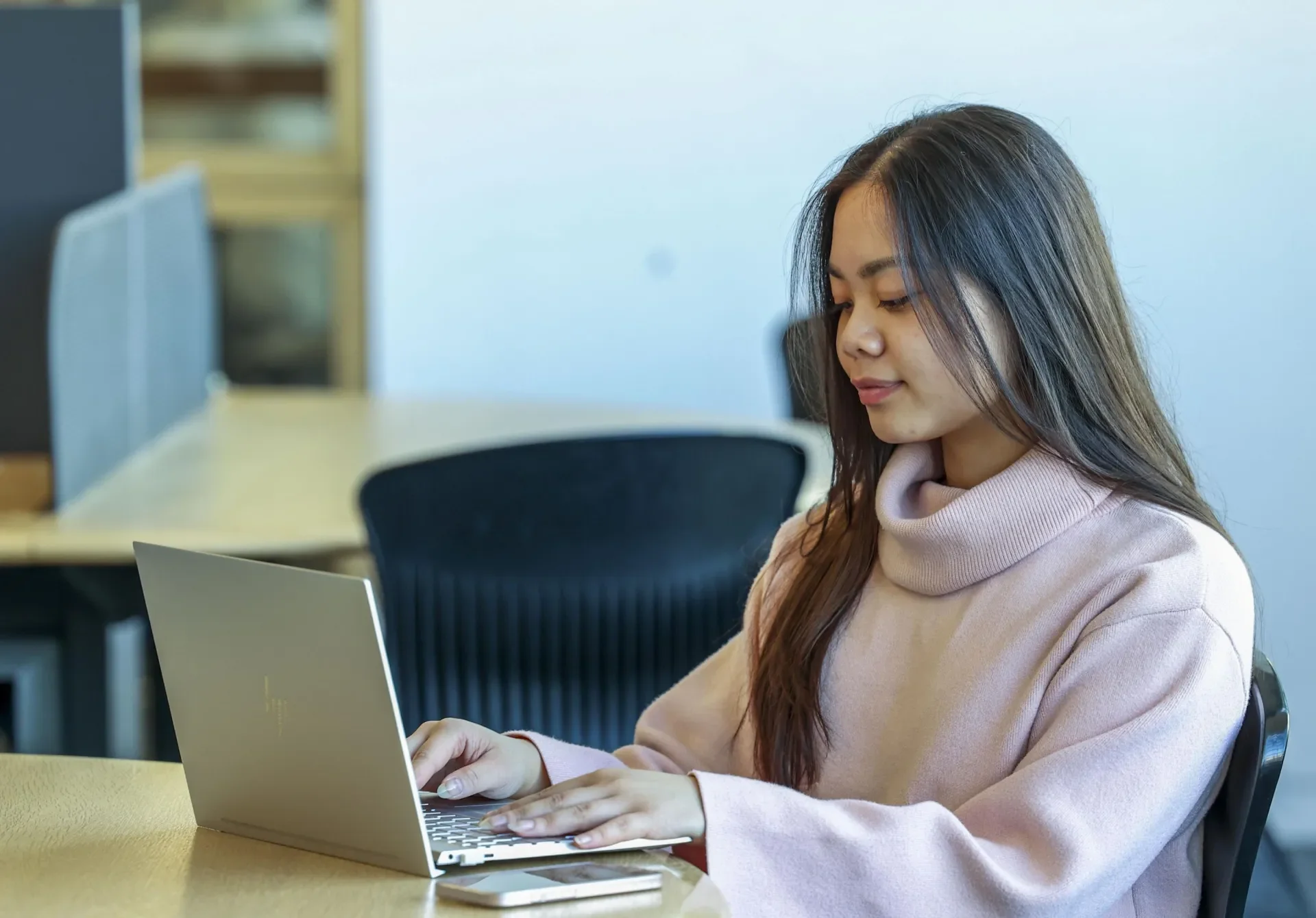 S student sitting at a desk in O'Reilly library working alone on a laptop