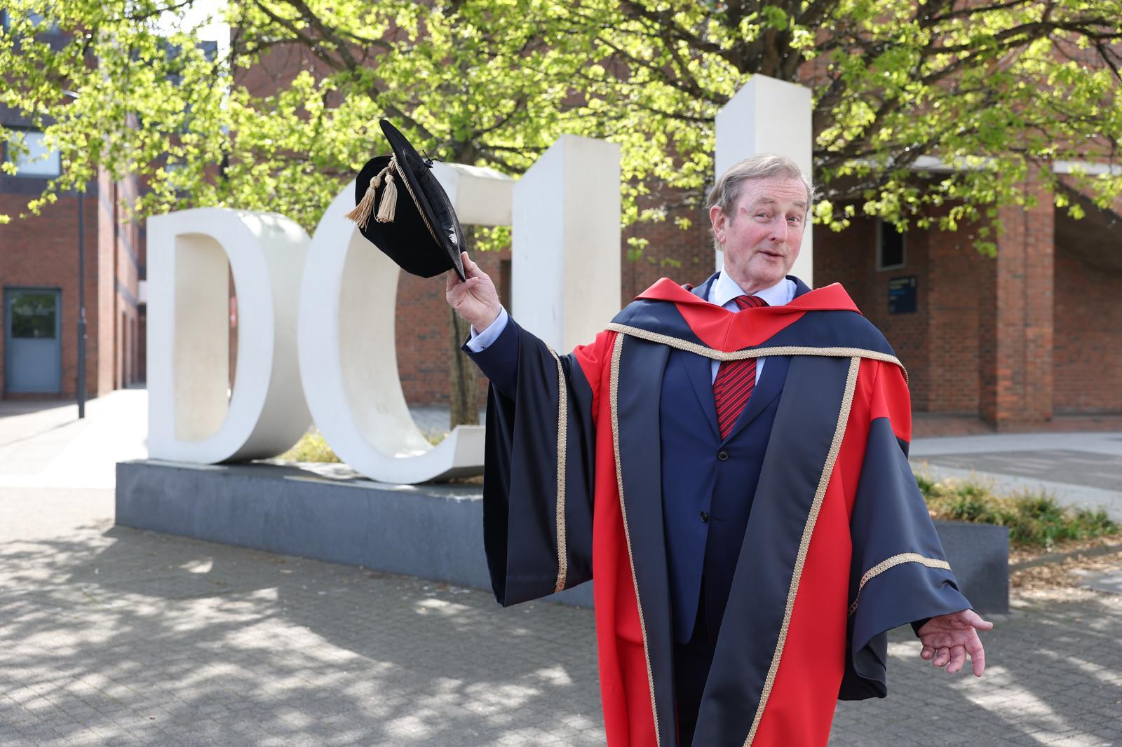 Enda Kenny stands at the DCU letters.