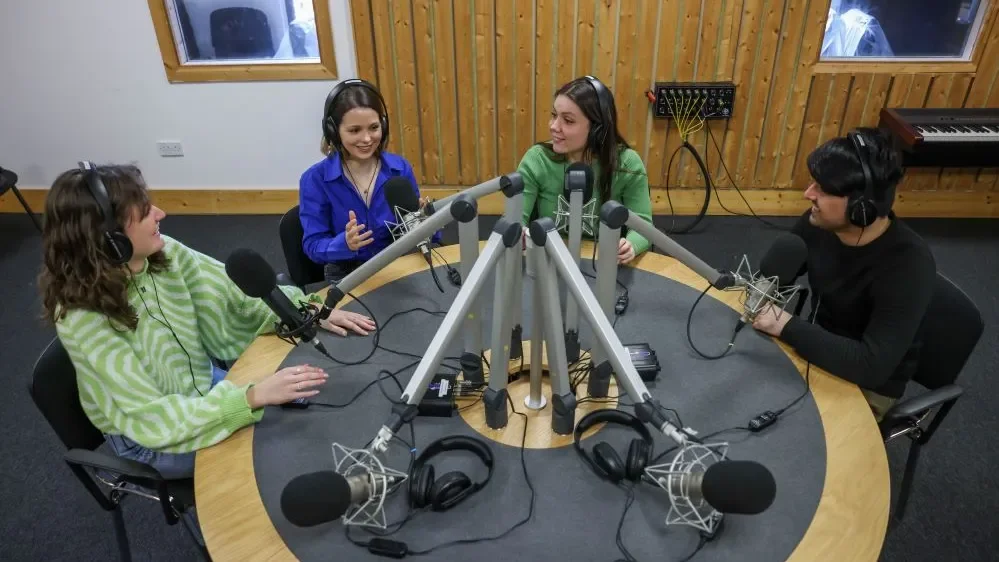 Students talking into microphones around a table